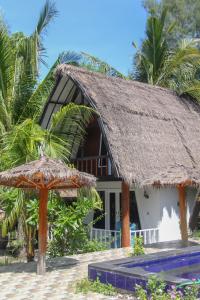 a house with a straw roof and two umbrellas at LUCKY'S in Gili Air