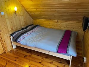 Bett in einer Holzhütte mit Holzboden in der Unterkunft Ranczo Targoszów in Targoszów