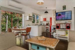 a kitchen and living room with a table and a tv at Byron Bay Accom - Frankies Beach House in Byron Bay