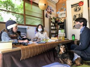 a group of people and a dog sitting at a table at Guest House Irodori Kamakura in Kamakura