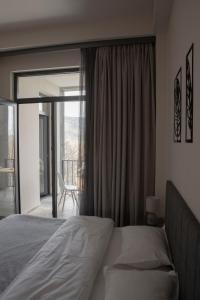 a bedroom with a bed and a window with a balcony at Monstera Leaf Appartment, Kechi House, Tsaghkadzor in Tsaghkadzor