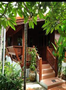 una casa con una escalera de madera que conduce a un porche en Thai authentic wooden house at Kata en Kata Beach