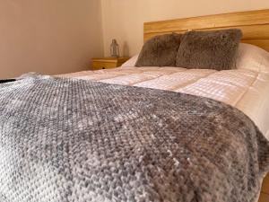ein Bett mit einer grau-weißen Decke darauf in der Unterkunft Casa Valentino Trattoria & Alojamiento in Mineral del Monte