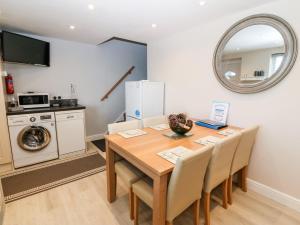 a dining room with a table and a kitchen with a washing machine at Sea Scape in Caernarfon