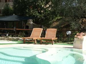 two chairs sitting next to a swimming pool at Belvilla by OYO Villa Max in Suvereto
