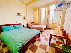 a bedroom with two beds and a table in it at Nụ Cười Xinh in Da Lat