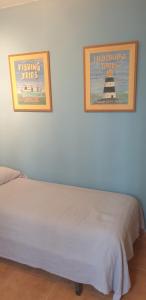 a bed with two pictures on the wall and a bedskirts at Apartamentos Atlanterra COSTA Y SOL in Zahara de los Atunes
