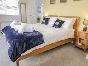 a large bed with blue and white sheets and pillows at 14 Parc Delfryn in Brynteg