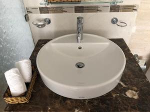 a white sink in a bathroom with towels on a counter at Rembrandt Hotel Nha Trang in Nha Trang