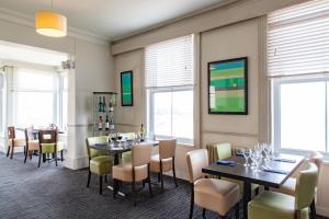 uma sala de jantar com mesas, cadeiras e janelas em The Norbreck Hotel em Scarborough
