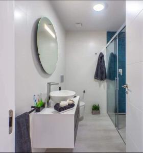 uma casa de banho branca com um lavatório e um espelho em Le petit nid de Xanie em Orihuela