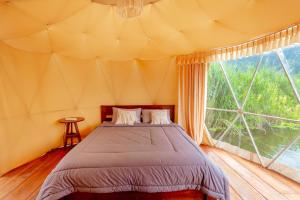 a bedroom with a bed in a tent with a large window at Jempana View in Kintamani