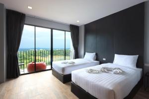 two beds in a room with a large window at The Wind Hotel in Bang Sare