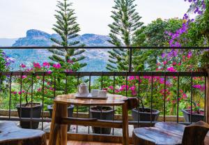 einen Balkon mit einem Tisch, Stühlen und Blumen in der Unterkunft Sceva's Garden Home in Munnar