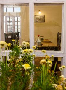 a dining room with a table and flowers in the foreground at Rosewood by Nature Resorts in Ooty