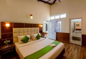 a bedroom with a large bed with green pillows at Rosewood by Nature Resorts and Stays in Ooty