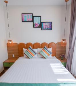 um quarto com uma grande cama branca com três fotografias na parede em The View Hotel em Cam Lâm