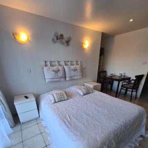 a bedroom with a large white bed and a table at Studios Les Iris in Monthou-sur-Cher