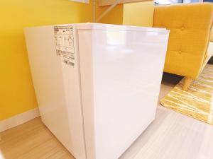 a white refrigerator in a room with a yellow wall at OUCHI HOTEL Nagarekawa with Dogs in Hiroshima