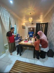 a group of people standing around a table in a kitchen at Damai Holiday Homestay in Melaka