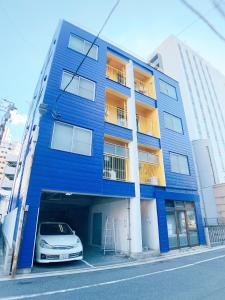 un edificio azul con un coche aparcado delante de él en OUCHI HOTEL Nagarekawa with Dogs en Hiroshima