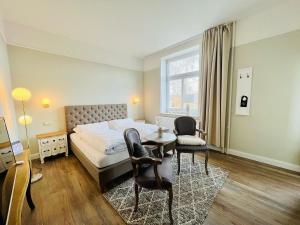 a bedroom with a bed and a table and chairs at Lexow - Hotel an de Havenkant in Tönning