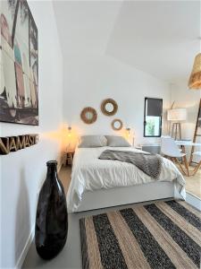 1 dormitorio con 1 cama y un jarrón en el suelo en Maisonnette à proximité plage et port de St-Martin, en Saint-Martin-de-Ré