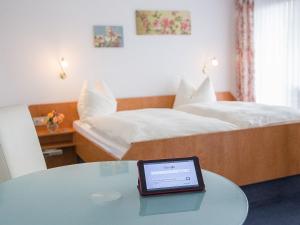 um quarto com uma cama e uma mesa com um tablet em Pension Huttental em Bad Soden-Salmünster