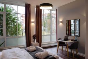 Schlafzimmer mit einem Bett, einem Schreibtisch und Fenstern in der Unterkunft HOMELY STAY Studio 7 in München