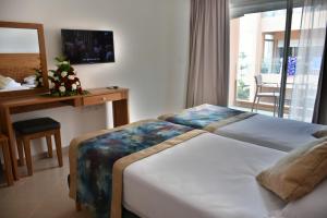 a bedroom with two beds and a desk and a window at Hotel Residence Imiplage in Agadir