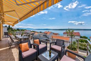 a balcony with tables and chairs and a view of the water at NOVOSELIC 7 Penthaus in Dramalj
