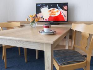 uma mesa de madeira com uma chávena de café e uma televisão em Pension Huttental em Bad Soden-Salmünster