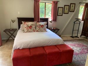 een slaapkamer met een groot bed en een rode poef bij Notting Hill Lodge in Balgowan