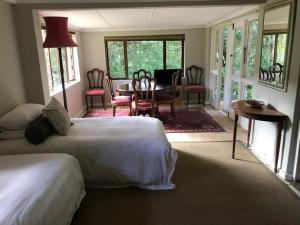Notting Hill Lodge في Balgowan: غرفة نوم بسريرين وطاولة وكراسي