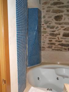 uma casa de banho com uma banheira e um chuveiro de azulejos azuis em Posada Real de Las Misas em Puebla de Sanabria
