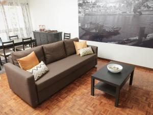 OPORTO GUEST Cedofeita Terrace في بورتو: غرفة معيشة مع أريكة بنية وطاولة