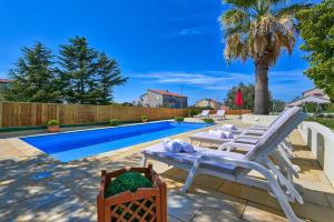 einen Hinterhof mit Pool und zwei Gartenstühlen in der Unterkunft Villa Oscar, Zadar in Zadar