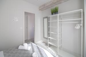 a white room with a bed and a book shelf at Apartamentos Teatro by Be Alicante in Alicante +32 photos