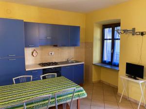 a kitchen with blue cabinets and a table with chairs at Residenza Graziella in Bobbio Pellice