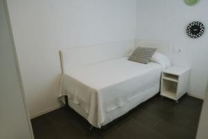 a bedroom with a white bed and a small table at Apartamentos ZHR 2 in Zahara de los Atunes
