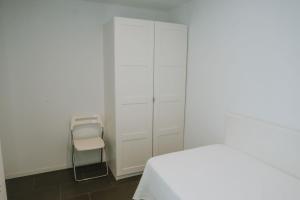 a white bedroom with a bed and a chair at Apartamentos ZHR 2 in Zahara de los Atunes