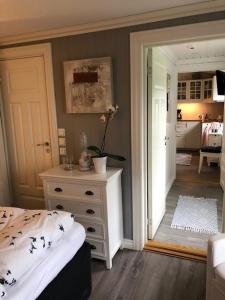 a bedroom with a bed and a dresser and a kitchen at Koselig leilighet sentralt i Stavern in Stavern