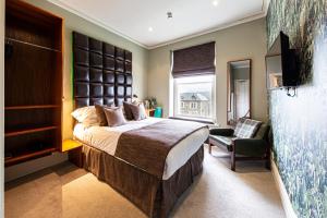 a bedroom with a large bed and a chair at Escape Boutique B&B in Llandudno