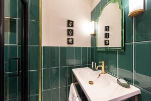 a green tiled bathroom with a sink and a mirror at Escape Boutique B&B in Llandudno