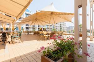 a patio with tables and chairs and umbrellas at Decor in Atlantis Resort&SPA by RV Apartments in Burgas