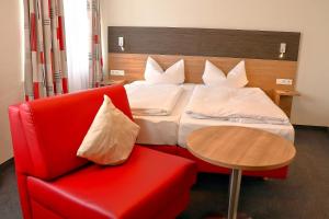 ハイリゲンベルクにあるBayerischer Hofの赤い椅子とベッドが備わるホテルルームです。