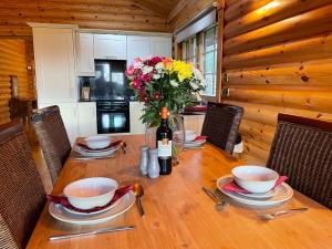a dining room table with a bottle of wine and flowers at Bunnahahbain - Two Bedroom Luxury Log Cabin with Private Hot Tub in Berwick-Upon-Tweed