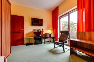 um quarto com uma secretária, uma cadeira e uma janela em Hotel Hermes em Krnov