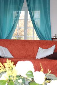 Sofá rojo con almohadas blancas y ventana en Rénovation proche lac et mer, en Landevieille