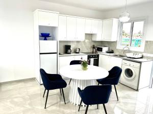 a white kitchen with a table and chairs in it at BLUE LATSI in Lachi +5 photos